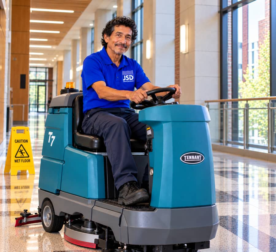 JSD Floor Technician operating a ride-on scrubber